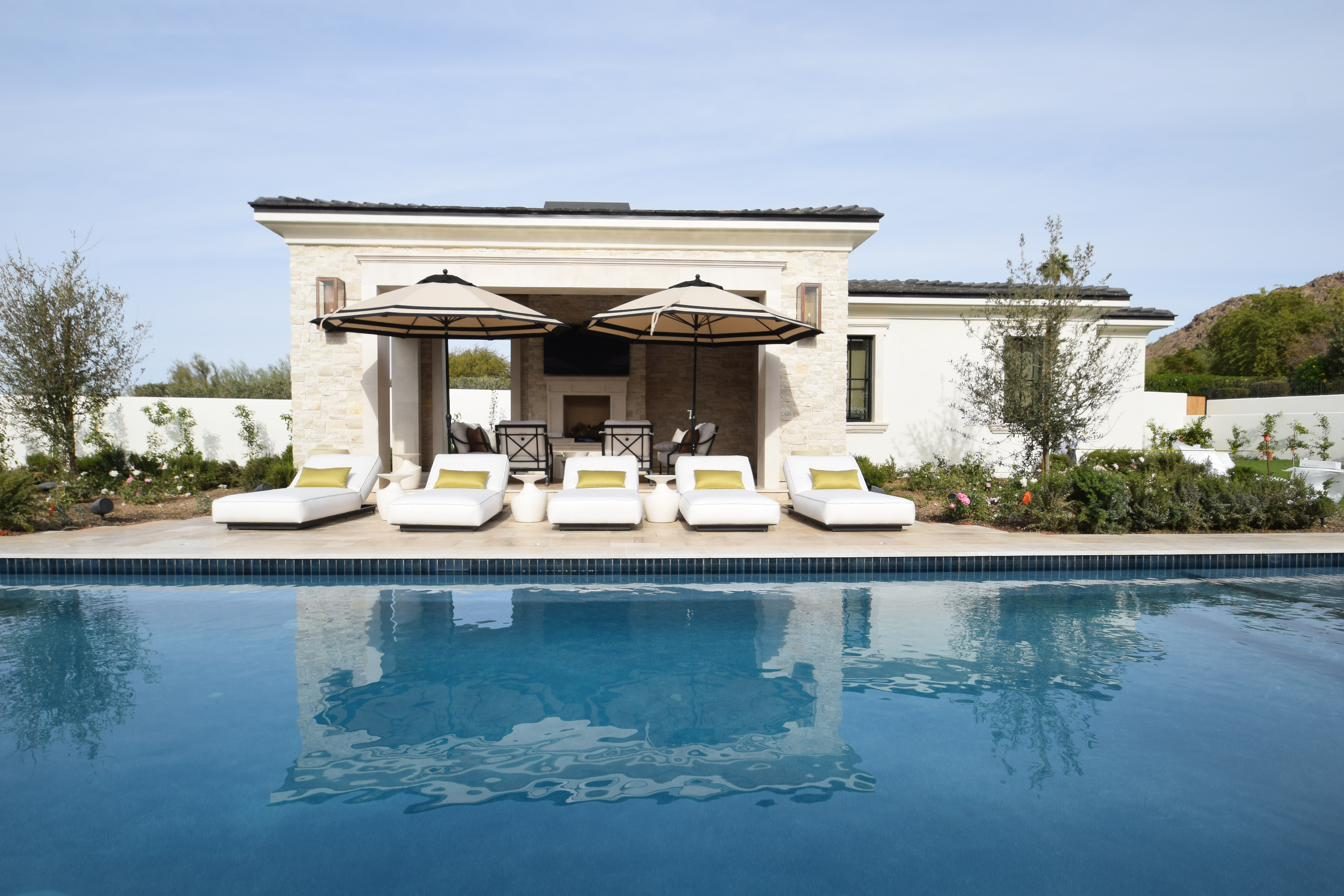Luxury poolside patio with restored white loungers at a desert estate