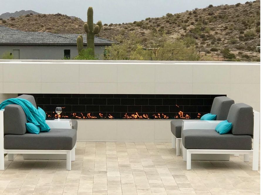 Modern outdoor fireplace lounge with restored gray cushions and teal accents